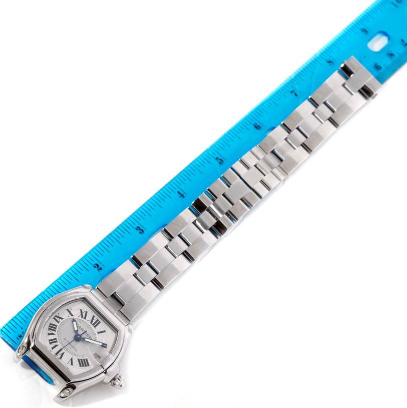 The image shows a Cartier Roadster W62000V3 Men's Stainless Steel Silver Dial W62000V3 Men's Stainless Steel Silver Dial watch from an overhead angle, with the full bracelet and a blue ruler measuring its length.