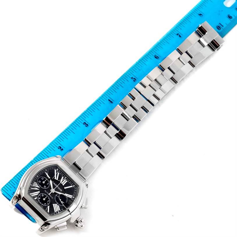 The Cartier Roadster W62020X6 Men's Stainless Steel Black Dial W62020X6 Men's Stainless Steel Black Dial watch is shown at an angle with its band aligned next to a blue ruler.