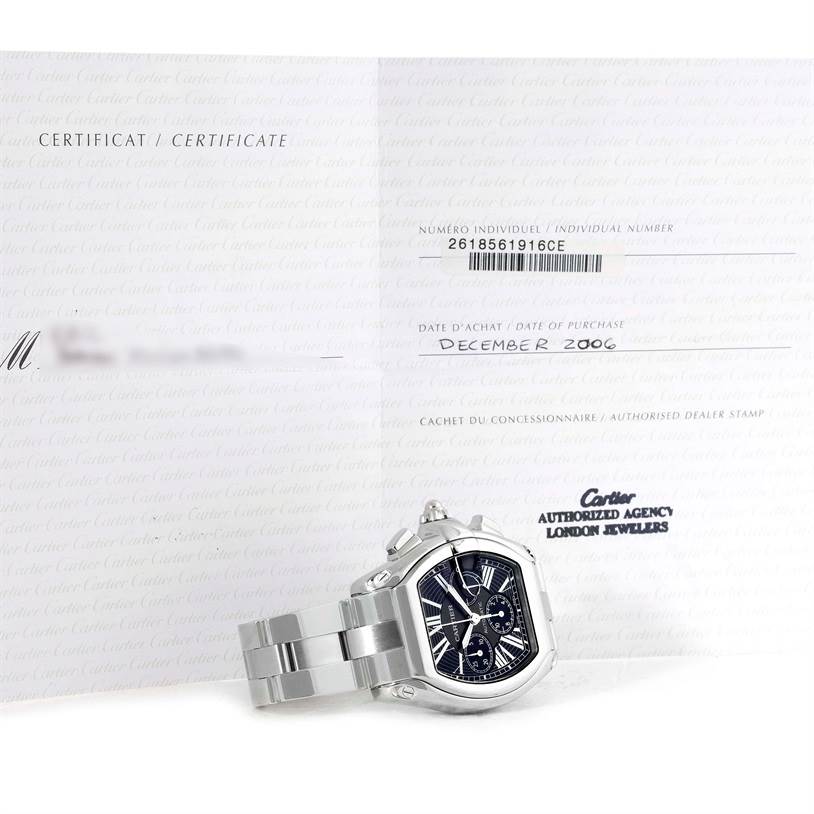 The image shows the Cartier Roadster W62020X6 Men's Stainless Steel Black Dial W62020X6 Men's Stainless Steel Black Dial watch at an angle displaying its face and part of the bracelet, along with the certification papers.
