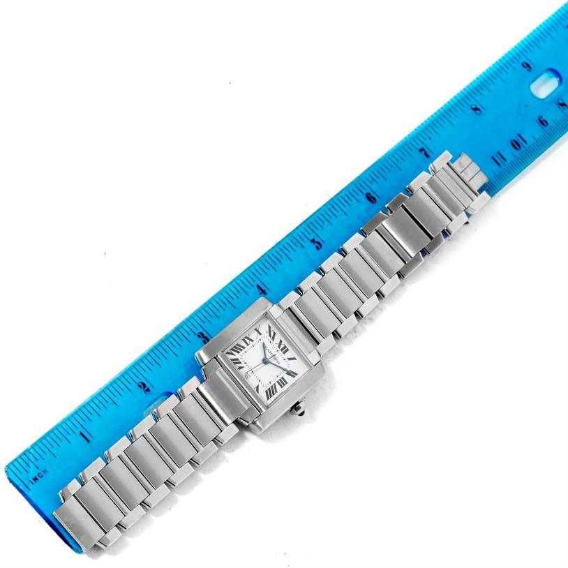 The image shows a Tank Francaise model by Cartier, laid flat next to a blue ruler for measurement, displaying the watch face and bracelet.