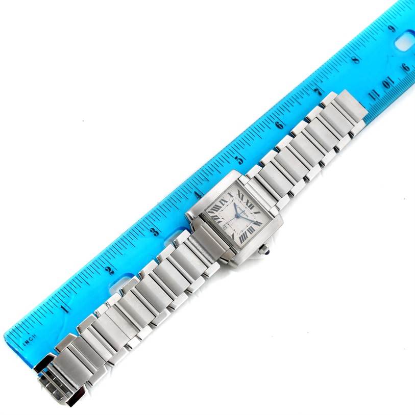 The image shows a top view of a Cartier Tank Française watch, including its face and metal bracelet, placed alongside a ruler for measurement.