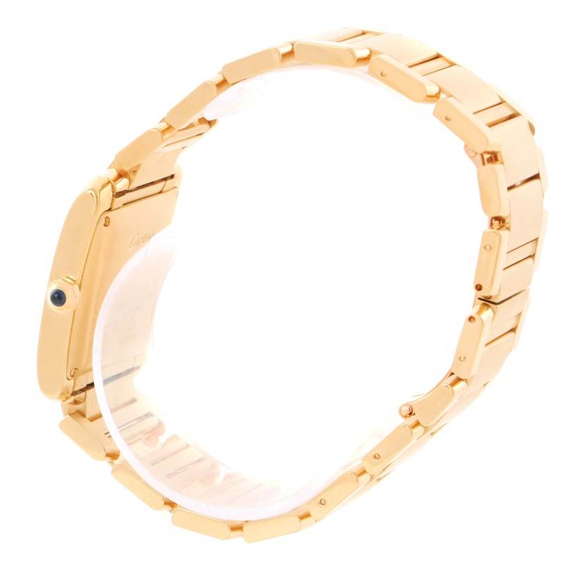 The image shows a side view of the Tank Française model by Cartier, highlighting the gold bracelet and crown with a blue gemstone.
