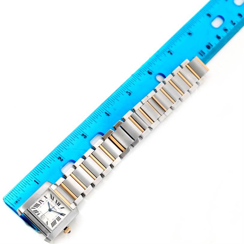 The image shows a Tank Française watch by Cartier, with a close-up of its face and bracelet beside a blue ruler for scale.