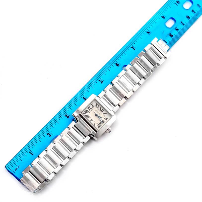 The Cartier Tank Francaise W50011S3 White Gold Silver Dial W50011S3 White Gold Silver Dial watch is shown from a top-down angle alongside a blue ruler, displaying its bracelet and face.