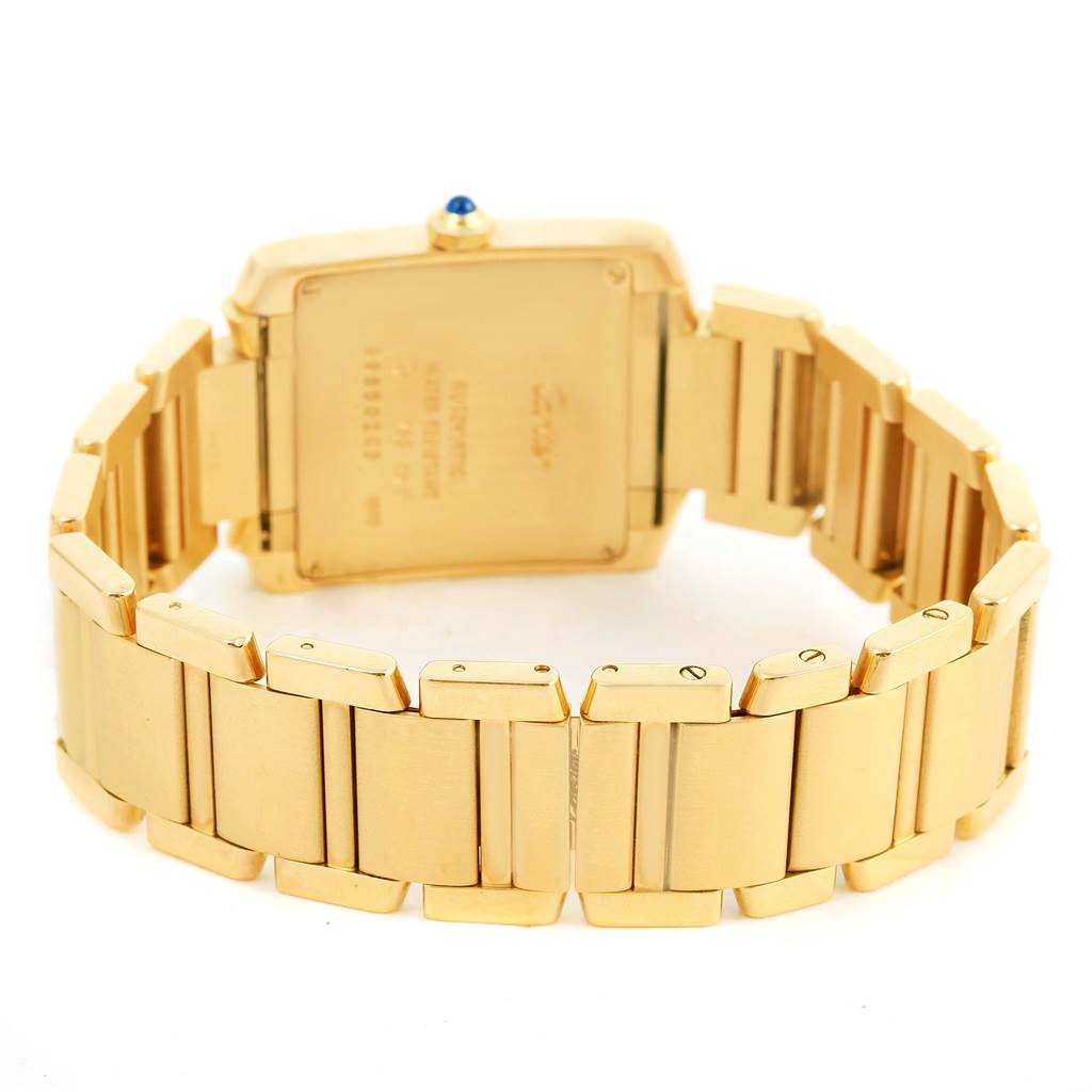 The image shows the back of a Cartier Tank Française watch, focusing on its gold bracelet and case with an end view of the crown.