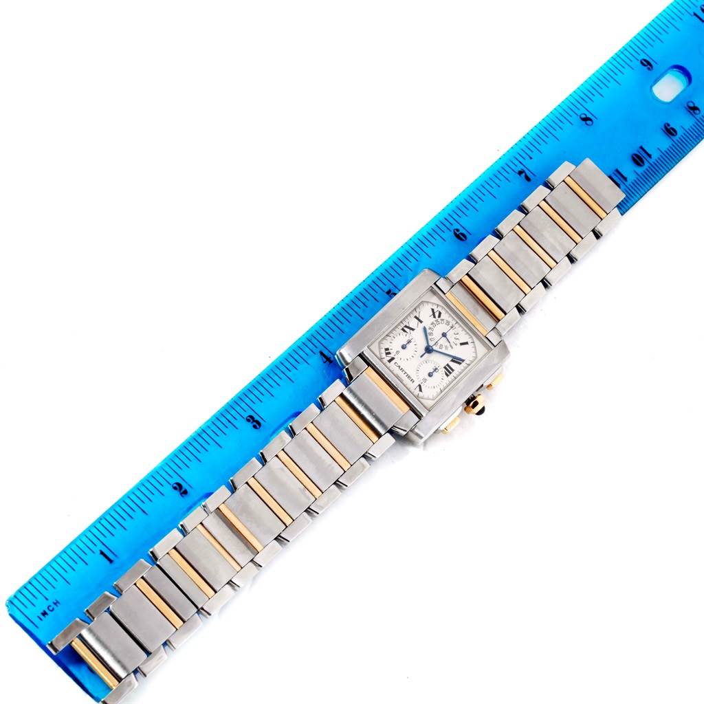 This image shows a Tank Française model watch by Cartier laid flat next to a blue ruler for measurement.