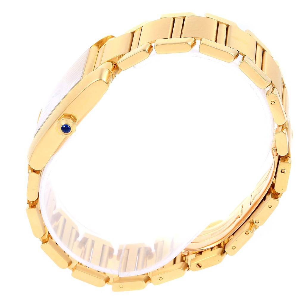 The image shows a side angle of a Cartier Tank Francaise W50001R2 Yellow Gold Silver Dial W50001R2 Yellow Gold Silver Dial watch, focusing on its gold bracelet and the crown with a blue cabochon.