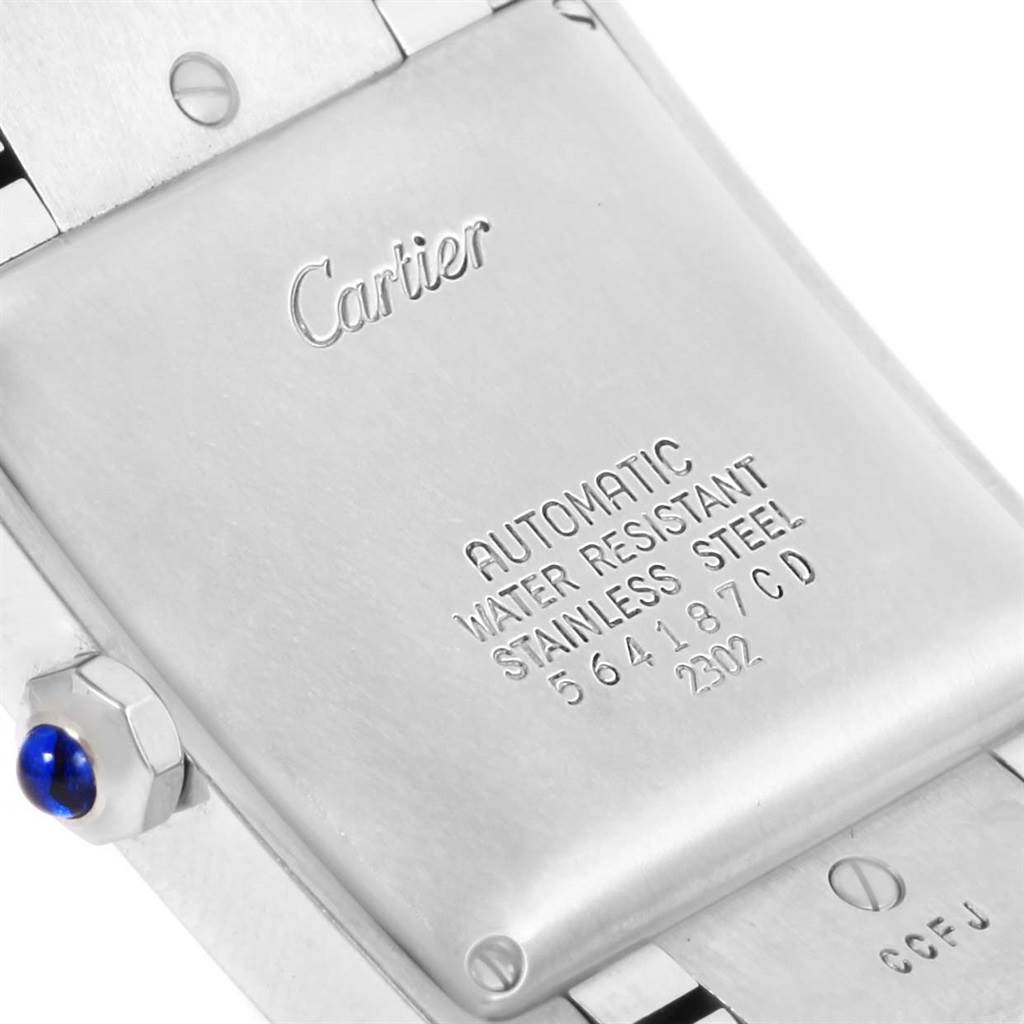 The image shows the back case and part of the bracelet of a Cartier Tank Française watch, highlighting its engravings and crown with a blue gem.
