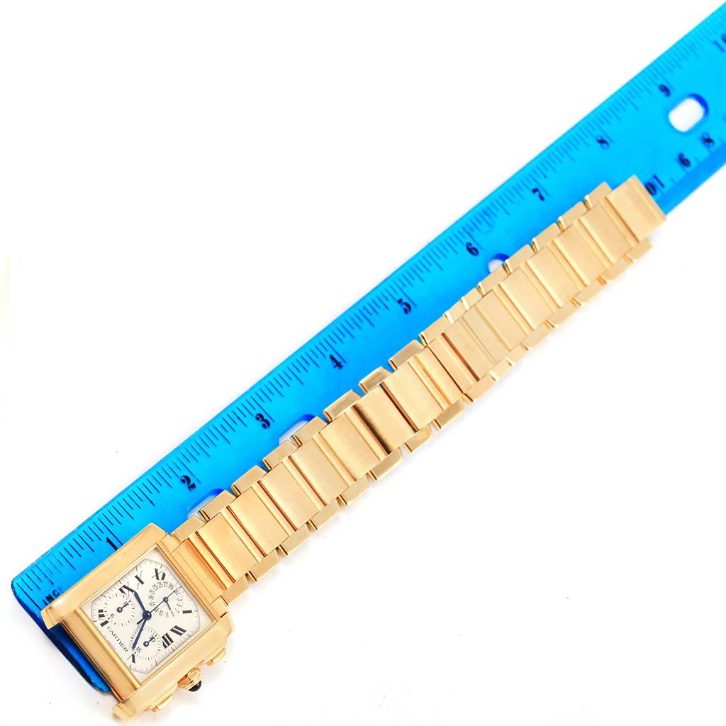 The Cartier Tank Francaise W50005R2 Men
s Yellow Gold Silver Dial W50005R2 Men
s Yellow Gold Silver Dial watch is shown from a top-down angle, displaying the face and bracelet next to a ruler for scale.