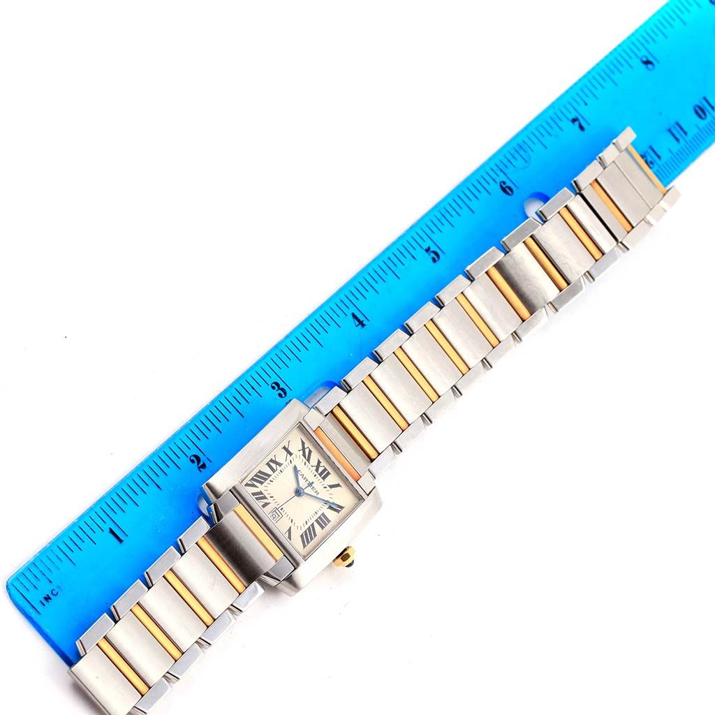 The image shows a top-down view of the Cartier Tank Française watch with its bracelet measured against a blue ruler.