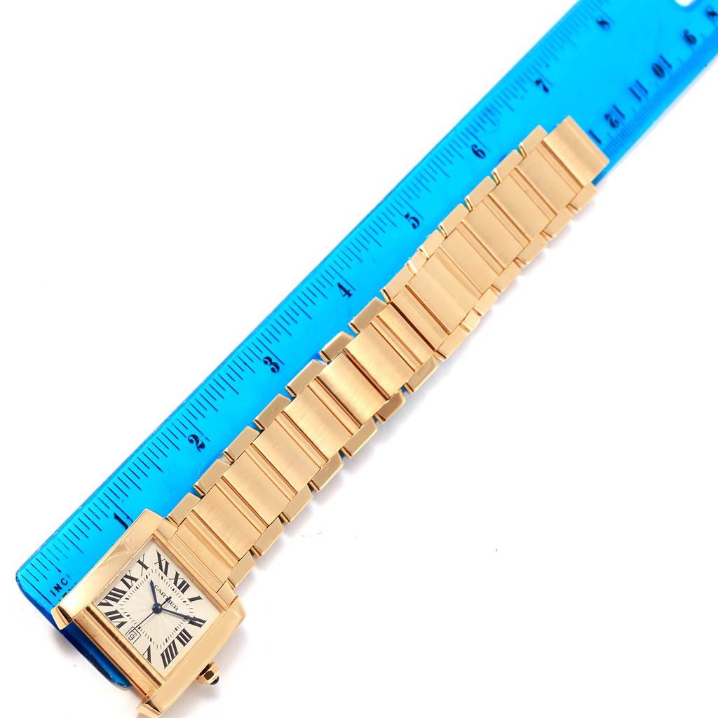 This image shows a Cartier Tank Française watch laid flat next to a ruler, detailing the face and full length of its metal bracelet.