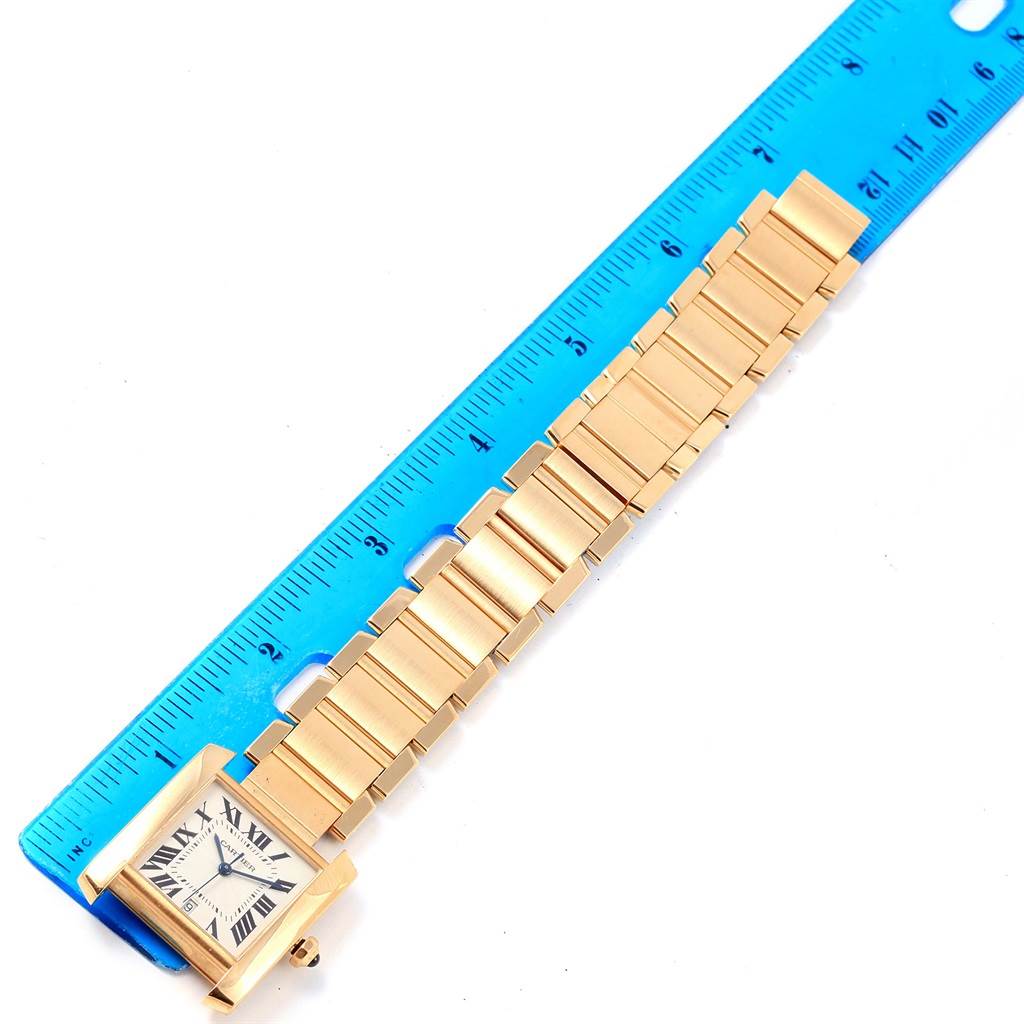 The Cartier Tank Francaise W50001R2 Men's Yellow Gold Silver Dial W50001R2 Men's Yellow Gold Silver Dial watch is shown face-up, with a ruler placed alongside its gold bracelet for measurement.