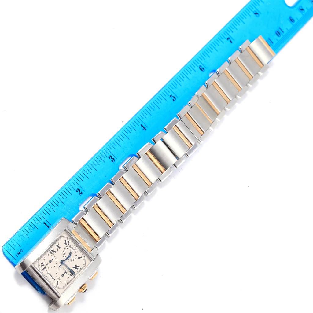 This image shows a Cartier Tank Francaise W51004Q4 Men's Steel and Gold (two tone) Silver Dial W51004Q4 Men's Steel and Gold (two tone) Silver Dial watch laid flat next to a blue ruler, showcasing its bracelet and watch face.