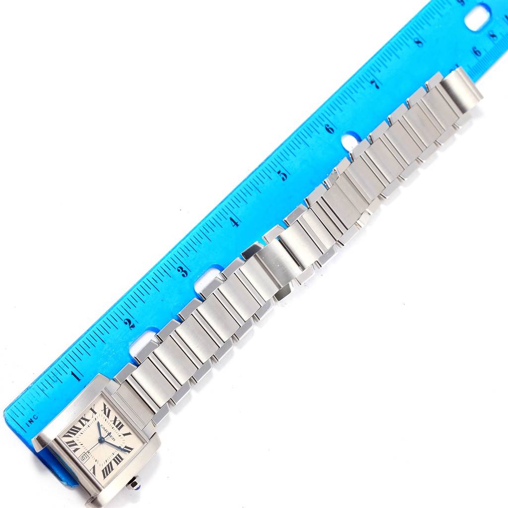 The image shows a Cartier Tank Francaise W51002Q3 Stainless Steel Silver Dial W51002Q3 Stainless Steel Silver Dial watch placed next to a blue ruler to measure its length.