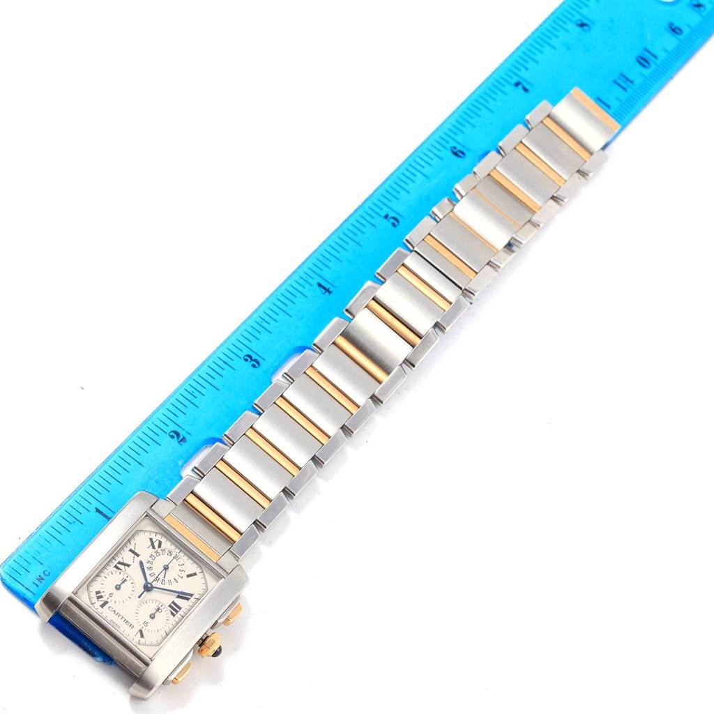 The Tank Française model by Cartier is shown in a top-down angle with the watch face and metal link bracelet displayed beside a ruler.