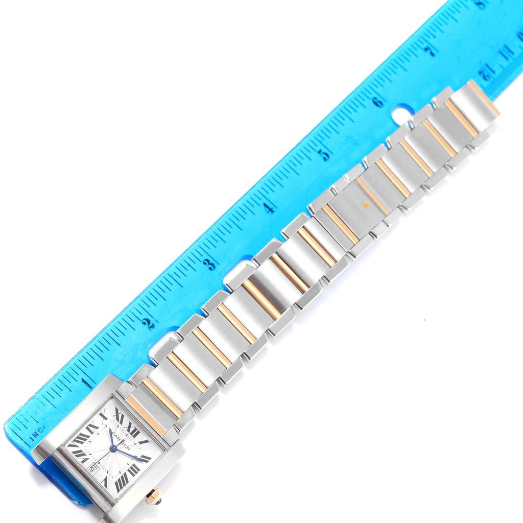 The image shows a Cartier Tank Francaise W51005Q4 Men
s Steel and Gold (two tone) Silver Dial W51005Q4 Men
s Steel and Gold (two tone) Silver Dial watch laid flat alongside a blue ruler, highlighting its bracelet and face.