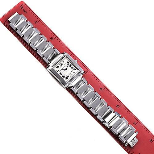 The Cartier Tank Française watch is shown fully extended on a red ruler, displaying the rectangular face and metal bracelet.