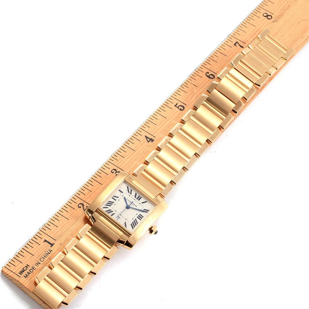 A gold Cartier Tank Francaise W50001R2 Yellow Gold Silver Dial W50001R2 Yellow Gold Silver Dial watch is shown from a top-down angle alongside a ruler, displaying its face and full bracelet length.