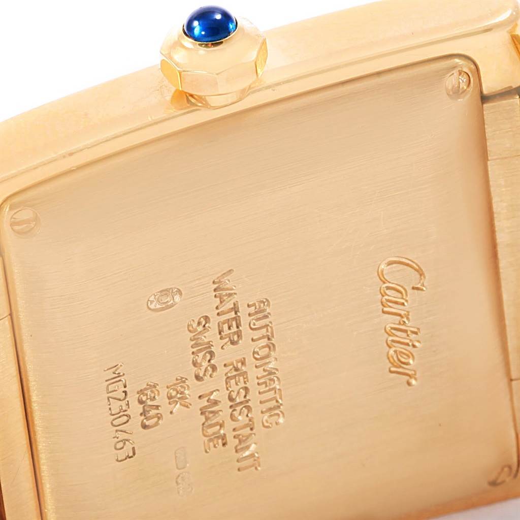 The image shows the back of the Cartier Tank Francaise W50001R2 Yellow Gold Silver Dial W50001R2 Yellow Gold Silver Dial watch, featuring inscriptions and part of the crown with a blue gemstone.