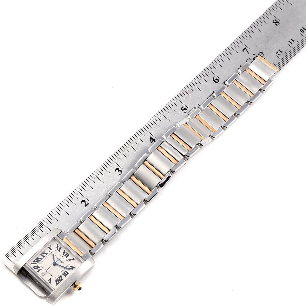 This image shows a Cartier Tank Francaise W51005Q4 Steel and Gold (two tone) Silver Dial W51005Q4 Steel and Gold (two tone) Silver Dial watch laid flat alongside a ruler, highlighting its chain links and rectangular face.