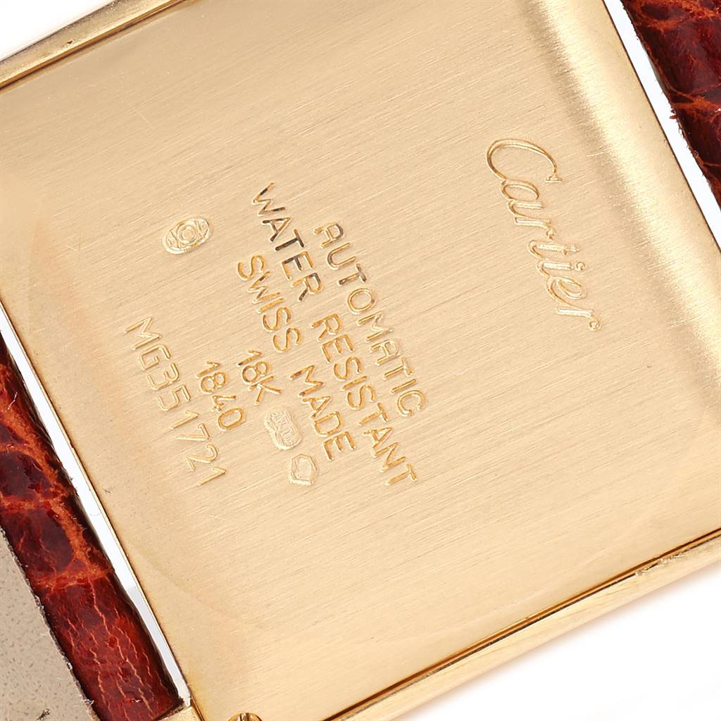 This image shows the case back of a Cartier Tank Francaise W5000156 Yellow Gold Silver Dial W5000156 Yellow Gold Silver Dial watch, including engravings and part of the leather strap.