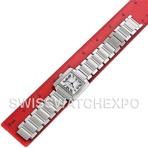 The Cartier Tank Française watch is shown from above, featuring its rectangular face and metal bracelet alongside a red ruler for scale.