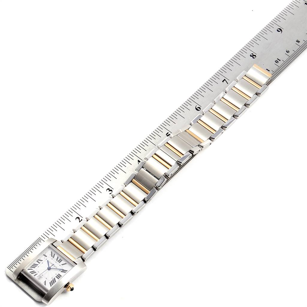 The image shows a Cartier Tank Française watch laid flat against a ruler, displaying the face and entire bracelet.