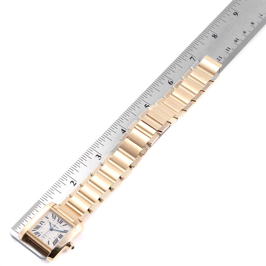 This image shows a Cartier Tank Française watch laid flat, alongside a ruler for scale.