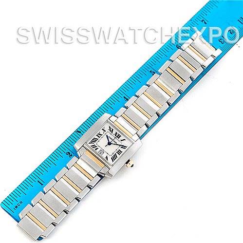 The Tank Francaise by Cartier is shown from a top-down angle, displaying its face and full bracelet laid next to a ruler.