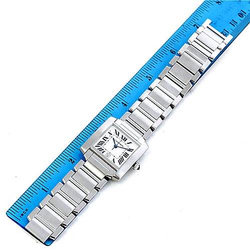 The image shows a Cartier Tank Française watch horizontally positioned next to a blue ruler for scale.