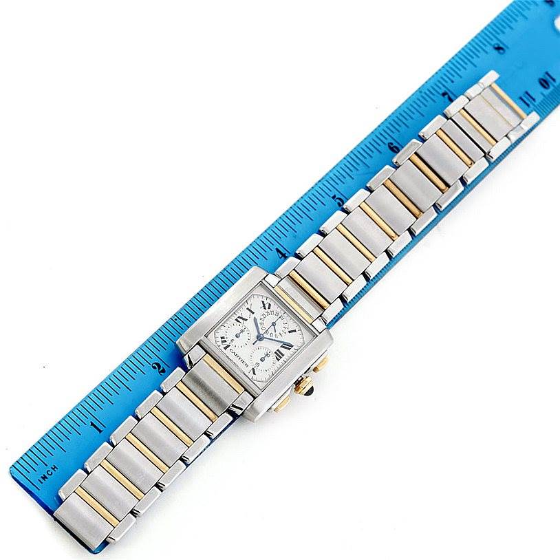 The Cartier Tank Française watch is shown from a top view, displaying its face and bracelet next to a ruler for scale.