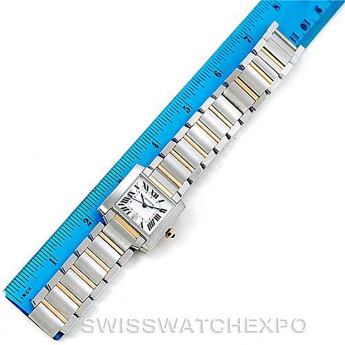 The Cartier Tank Française watch is shown diagonally with its full bracelet laid next to a blue ruler.