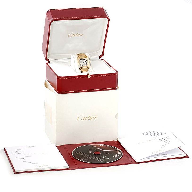 The image shows a Cartier Tank Francaise W50001R2 Men
s Yellow Gold Silver Dial W50001R2 Men
s Yellow Gold Silver Dial watch in its open box, with manuals and a CD laid out in front.