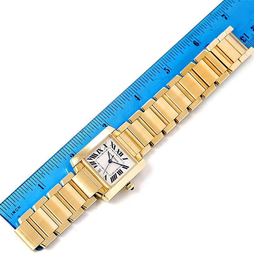 The image shows a top-view angle of a Cartier Tank Francaise W50001R2 Men
s Yellow Gold Silver Dial W50001R2 Men
s Yellow Gold Silver Dial watch next to a blue ruler, displaying the face and bracelet.