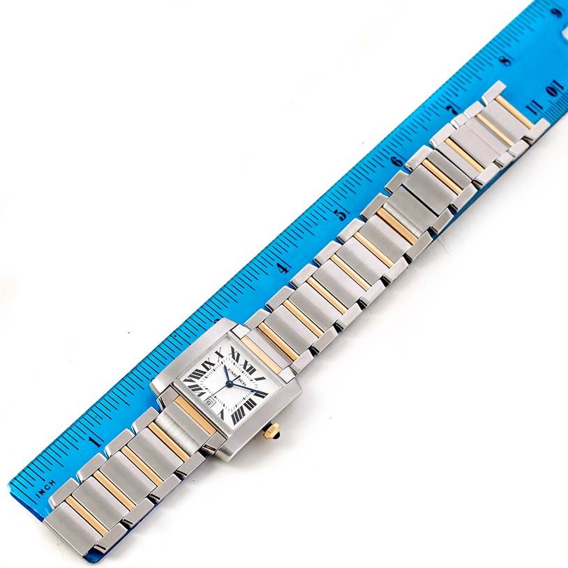 The Cartier Tank Francaise W51005Q4 Men
s Steel and Gold (two tone) Silver Dial W51005Q4 Men
s Steel and Gold (two tone) Silver Dial watch is shown in a top-down view next to a blue ruler, highlighting its bracelet and face.