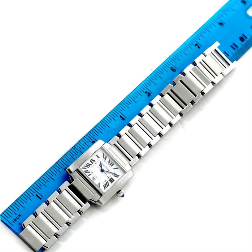 The Cartier Tank Française watch is shown from a top-down angle with its face, case, and bracelet visible, alongside a ruler.
