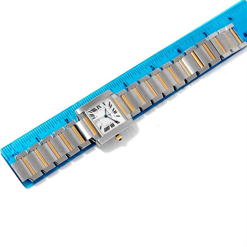 The image shows a Cartier Tank Française model watch laid flat with a blue ruler alongside it for size reference.