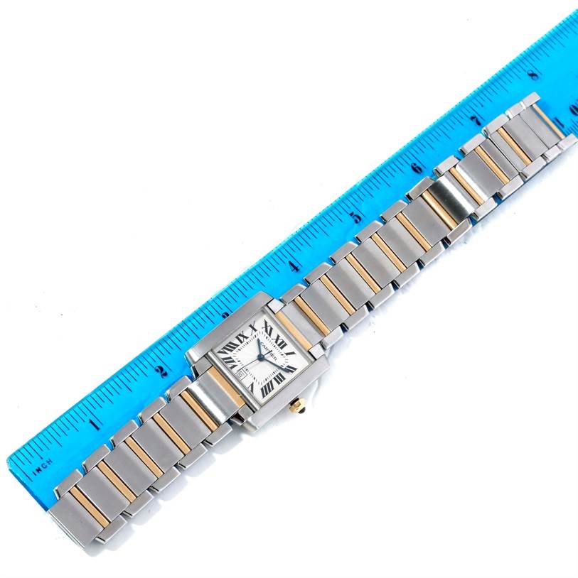 The image shows a top-down view of a Cartier Tank Française watch alongside a blue ruler for measurement.