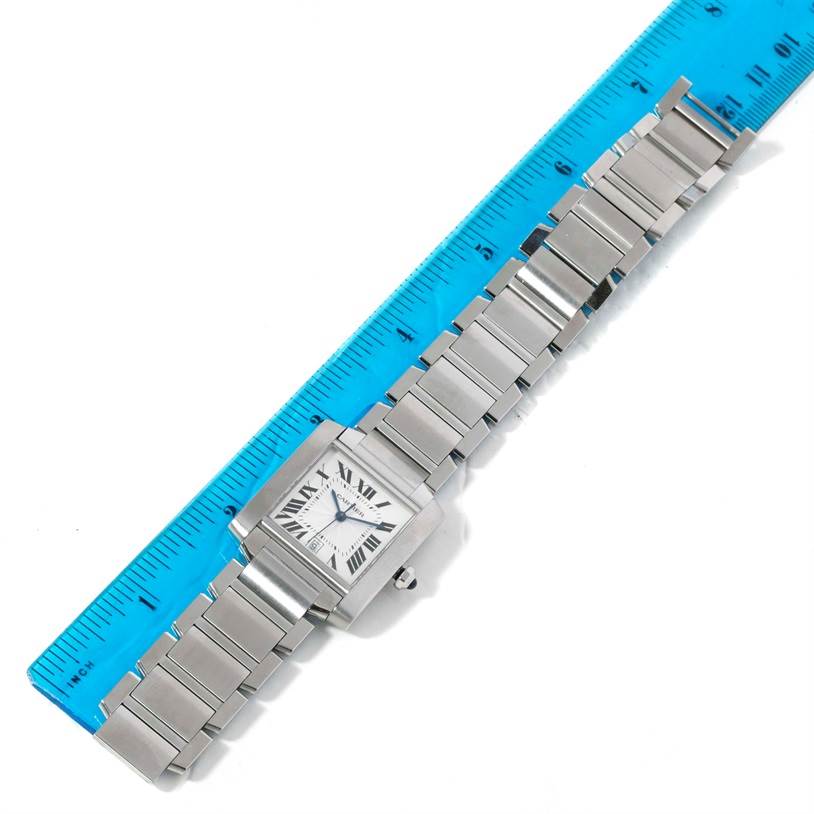 This image shows a Cartier Tank Française watch flat on a surface, aligned with a blue ruler.