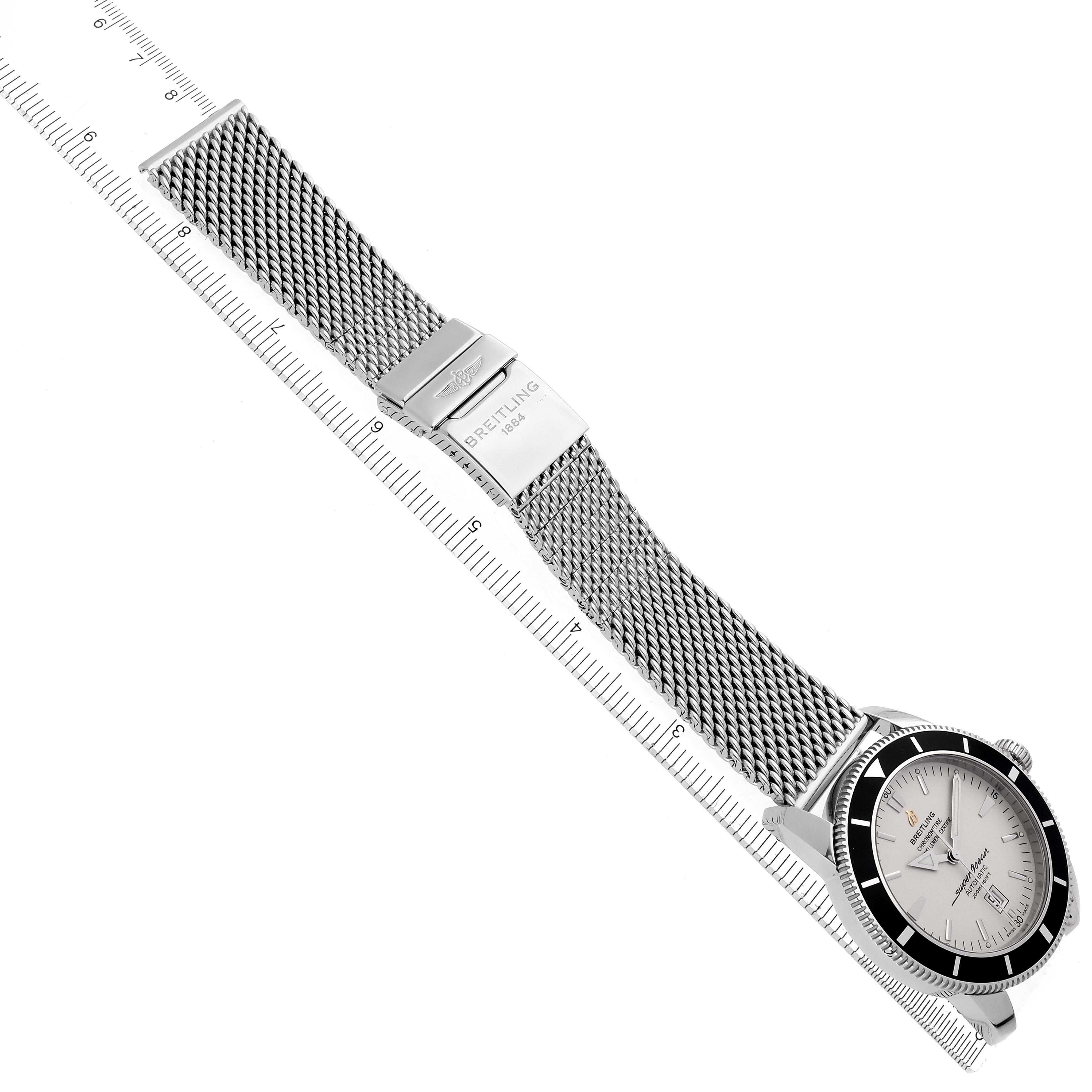 The Breitling Superocean A1732024/G642 Men's Stainless Steel Silver Dial A1732024/G642 Men's Stainless Steel Silver Dial watch is shown from a top view, highlighting the mesh bracelet and clasp, alongside a ruler.