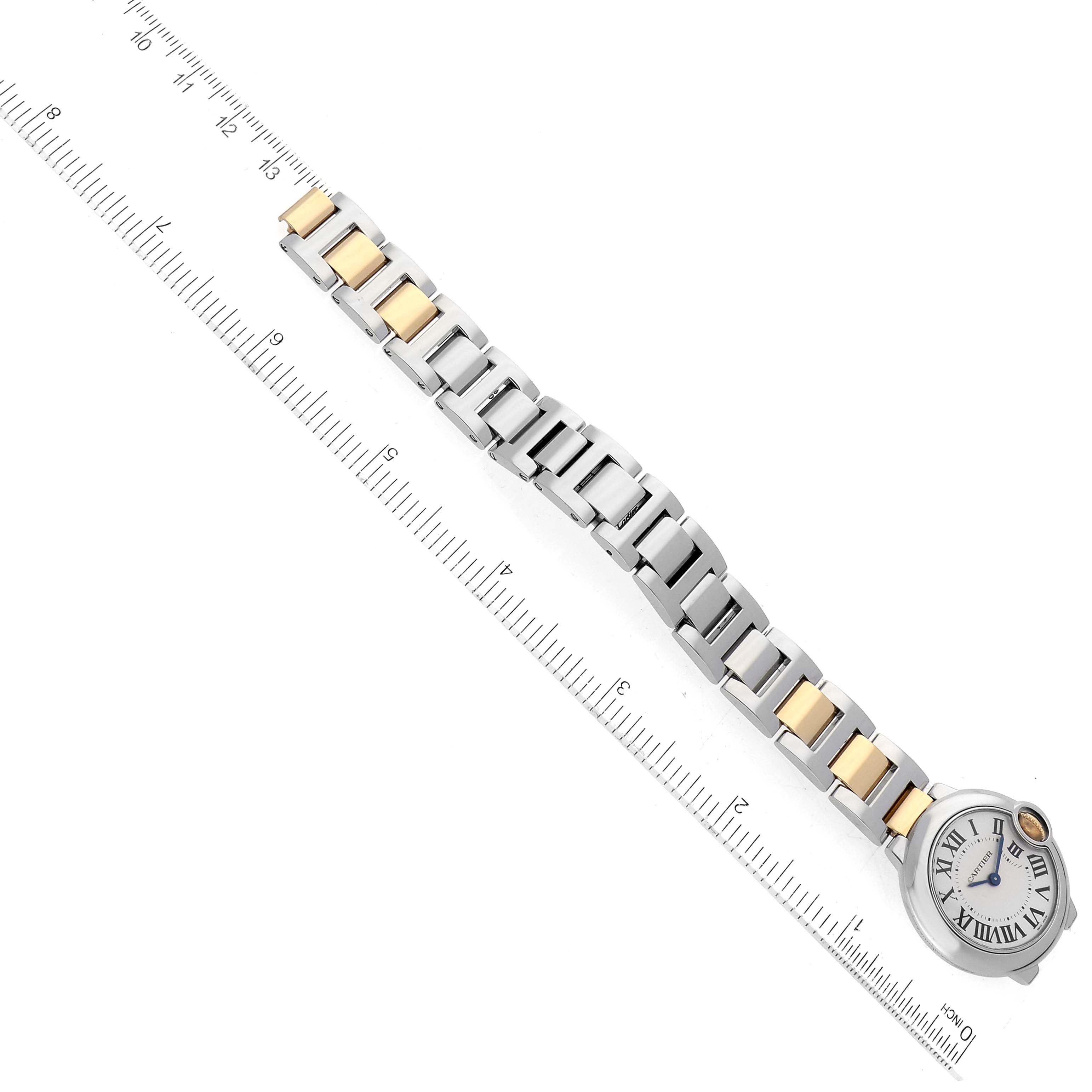 The image shows the Ballon Bleu model by Cartier placed diagonally, displaying its face, bracelet, and a measuring ruler in the background.