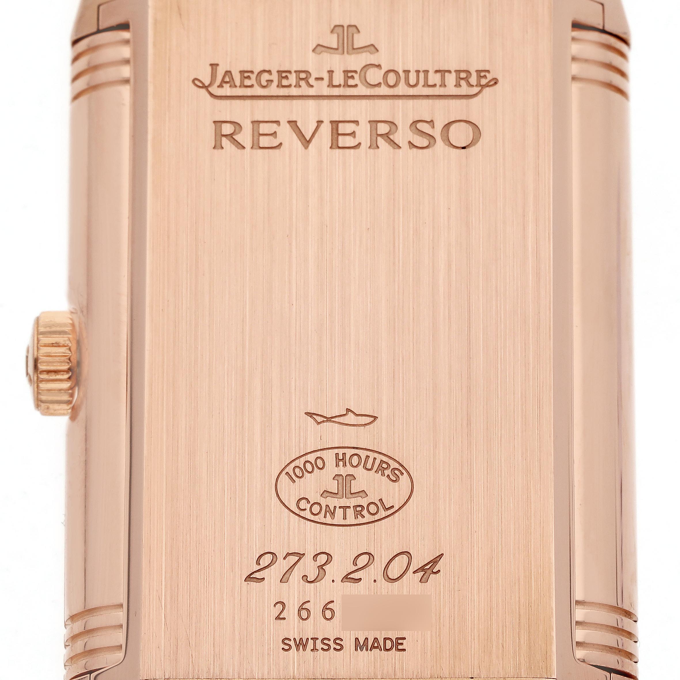 The image shows the back of a Jaeger-LeCoultre Reverso watch, highlighting its engravings and crown from a close-up angle.