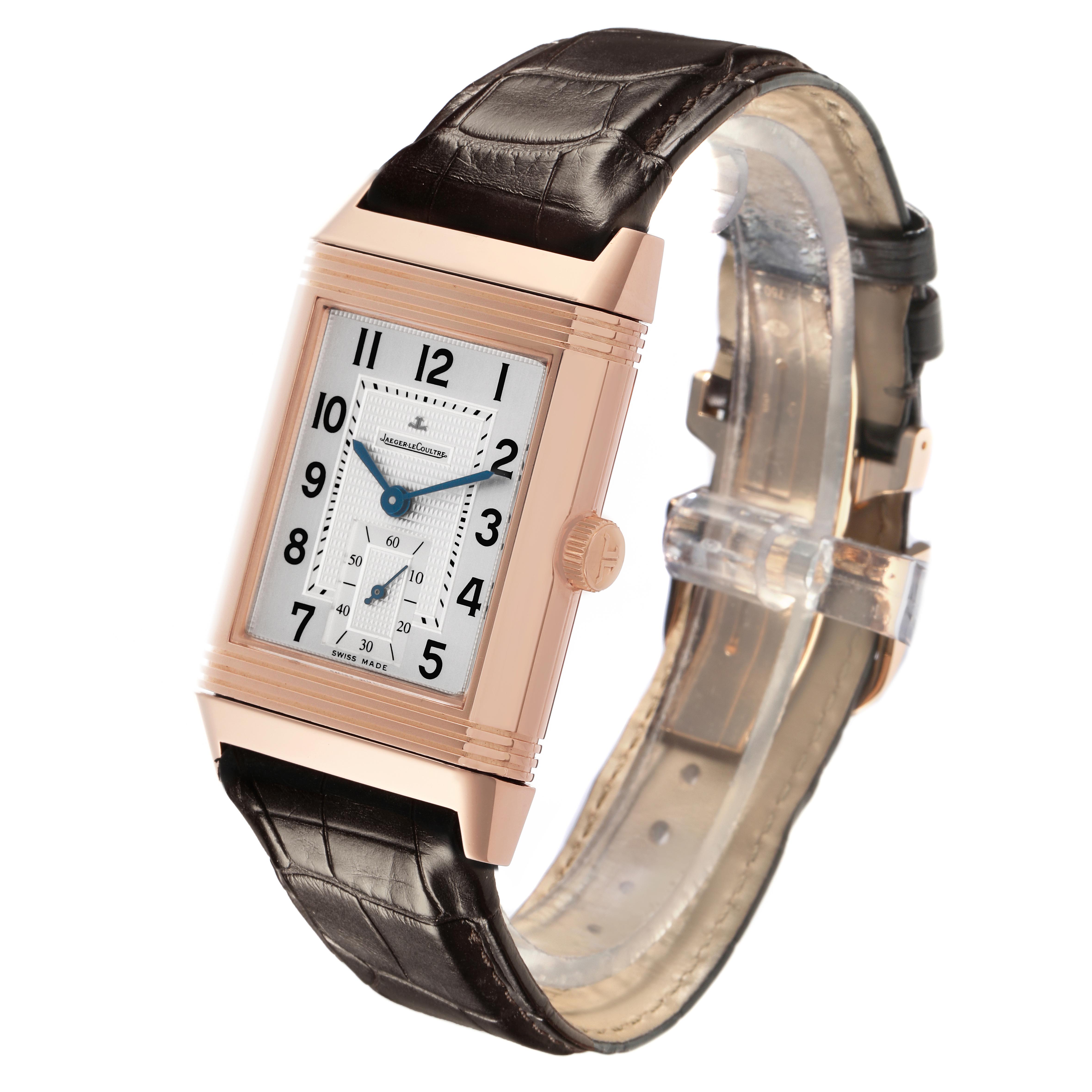 The Jaeger-LeCoultre Reverso watch is shown at a slight angle, highlighting the rectangular dial, leather strap, and crown.