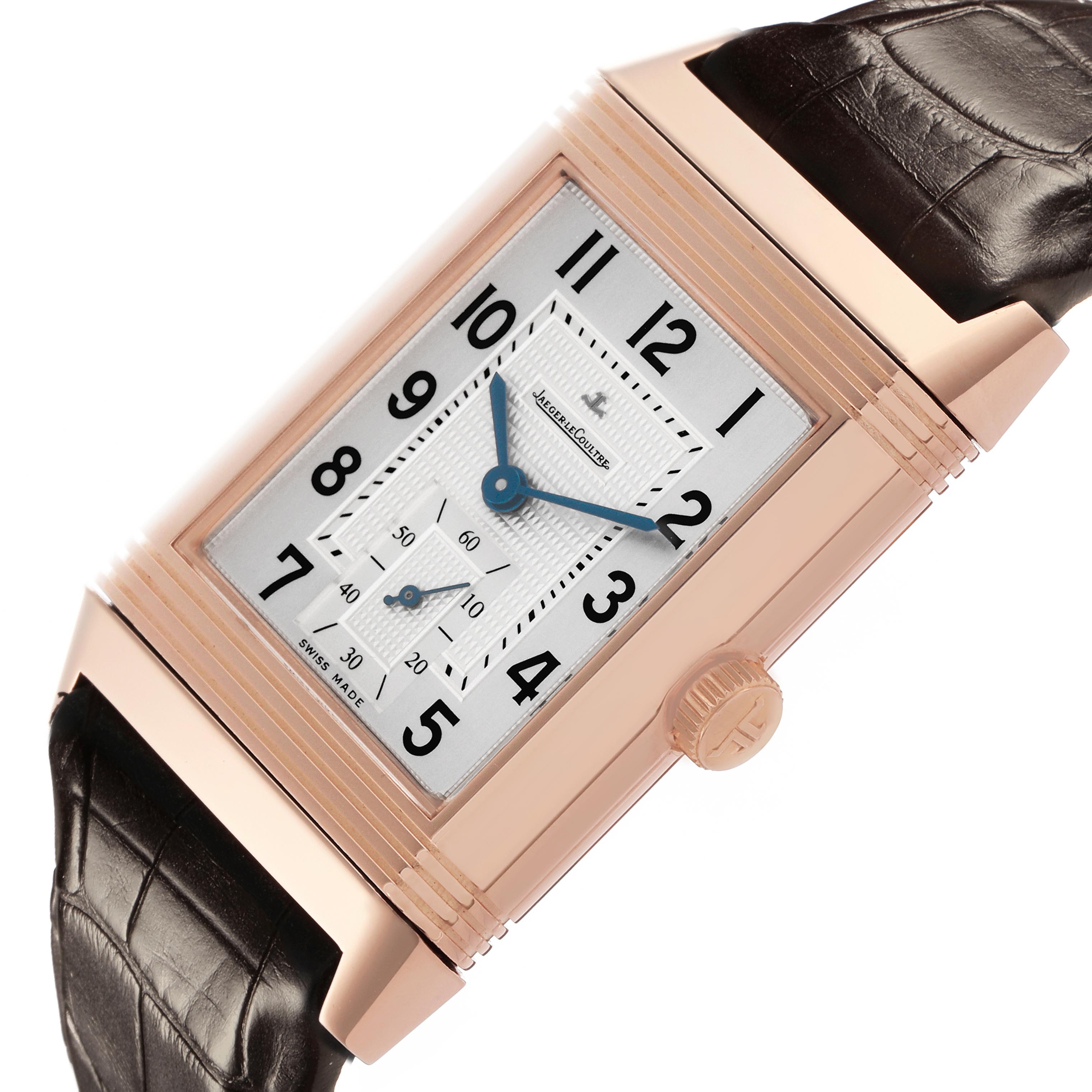The Jaeger-LeCoultre Reverso watch is shown at an angle displaying the face, case, crown, and leather strap.