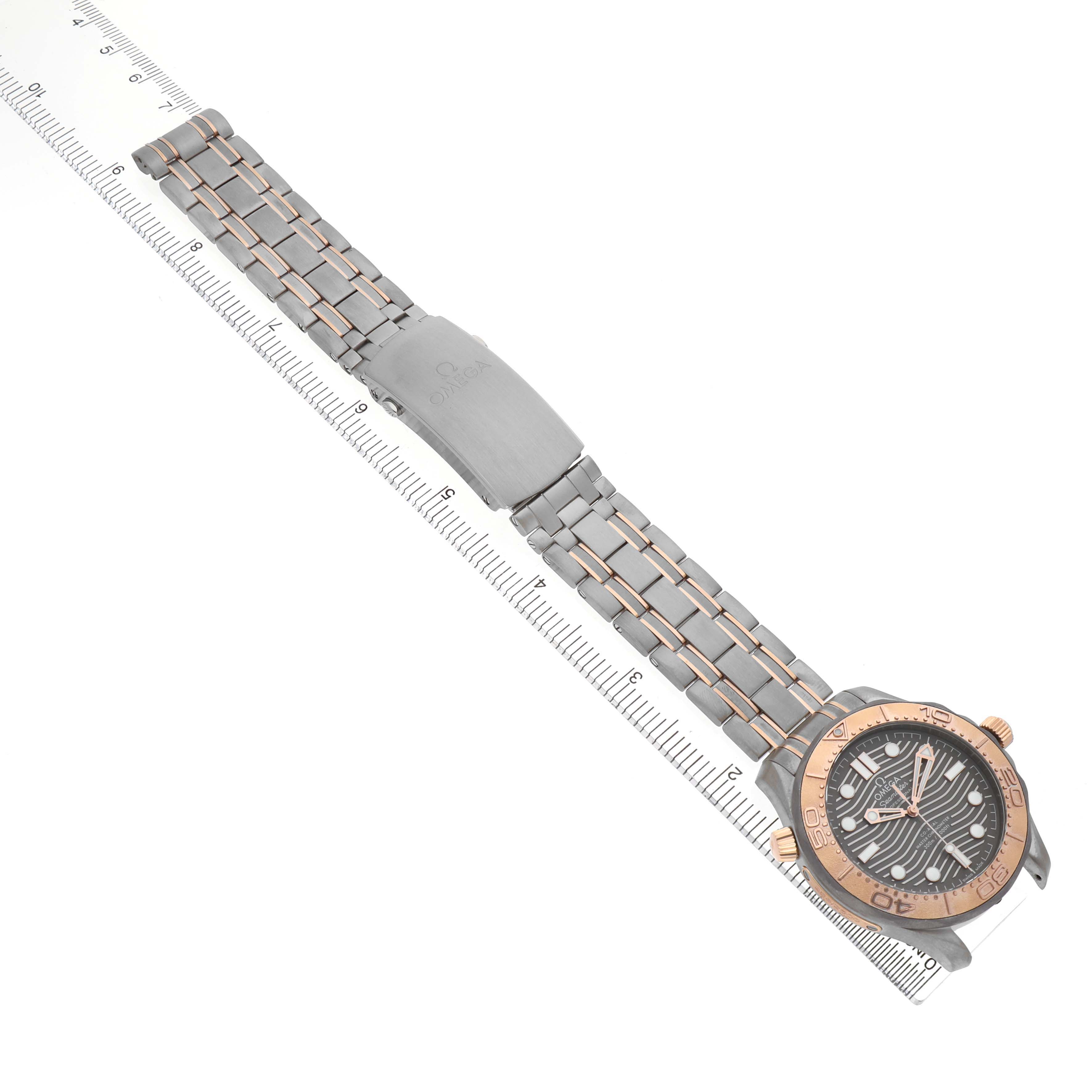 The Omega Seamaster 210.60.42.20.99.001 Men's Titanium Grey Dial watch is shown from a top-down angle, highlighting the face, bezel, and bracelet with a ruler for scale.