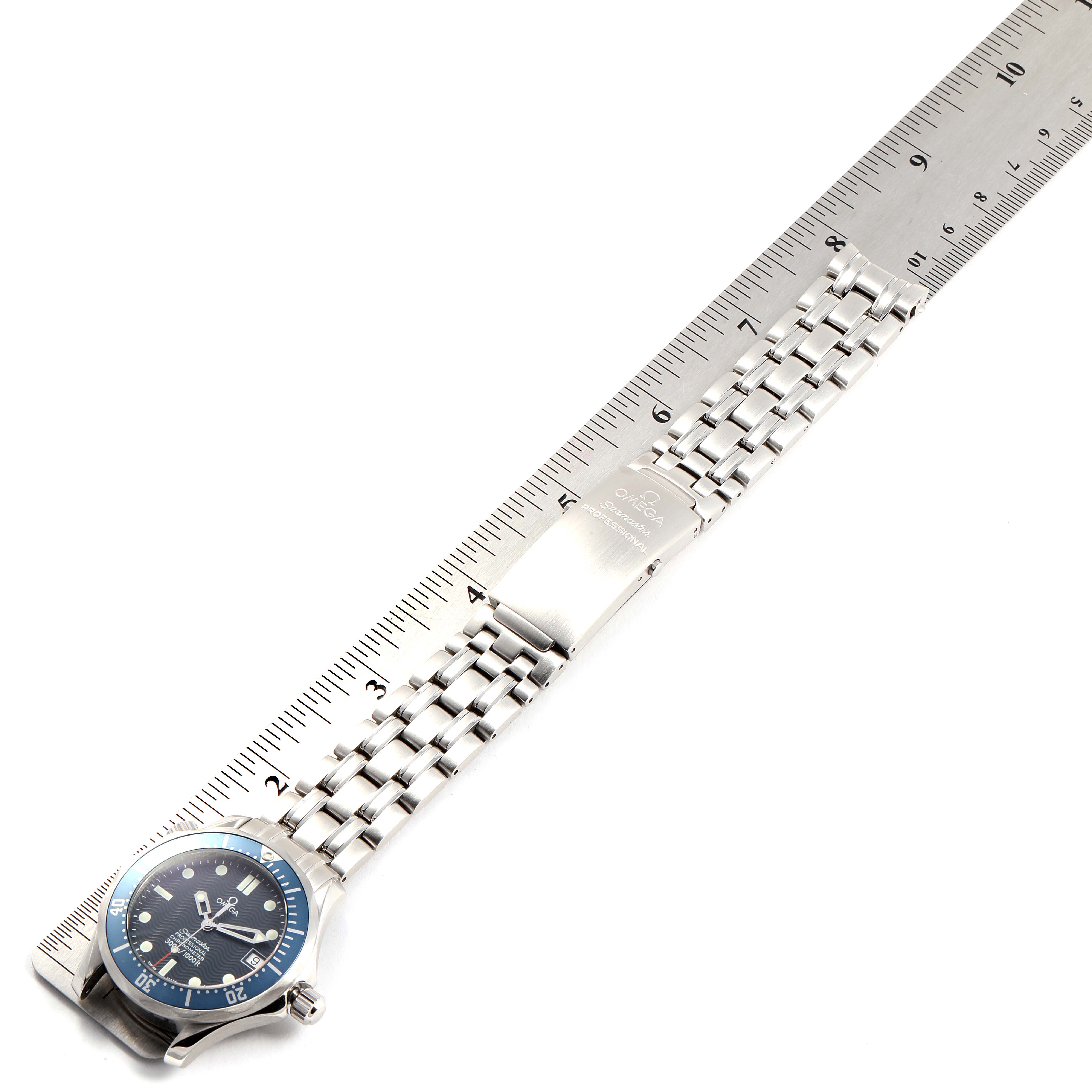 The image shows an Omega Speedmaster 2551.80.00 Men
s Stainless Steel Blue Dial 2551.80.00 Men
s Stainless Steel Blue Dial watch, positioned flat with its metal bracelet fully extended and a ruler for measurement.