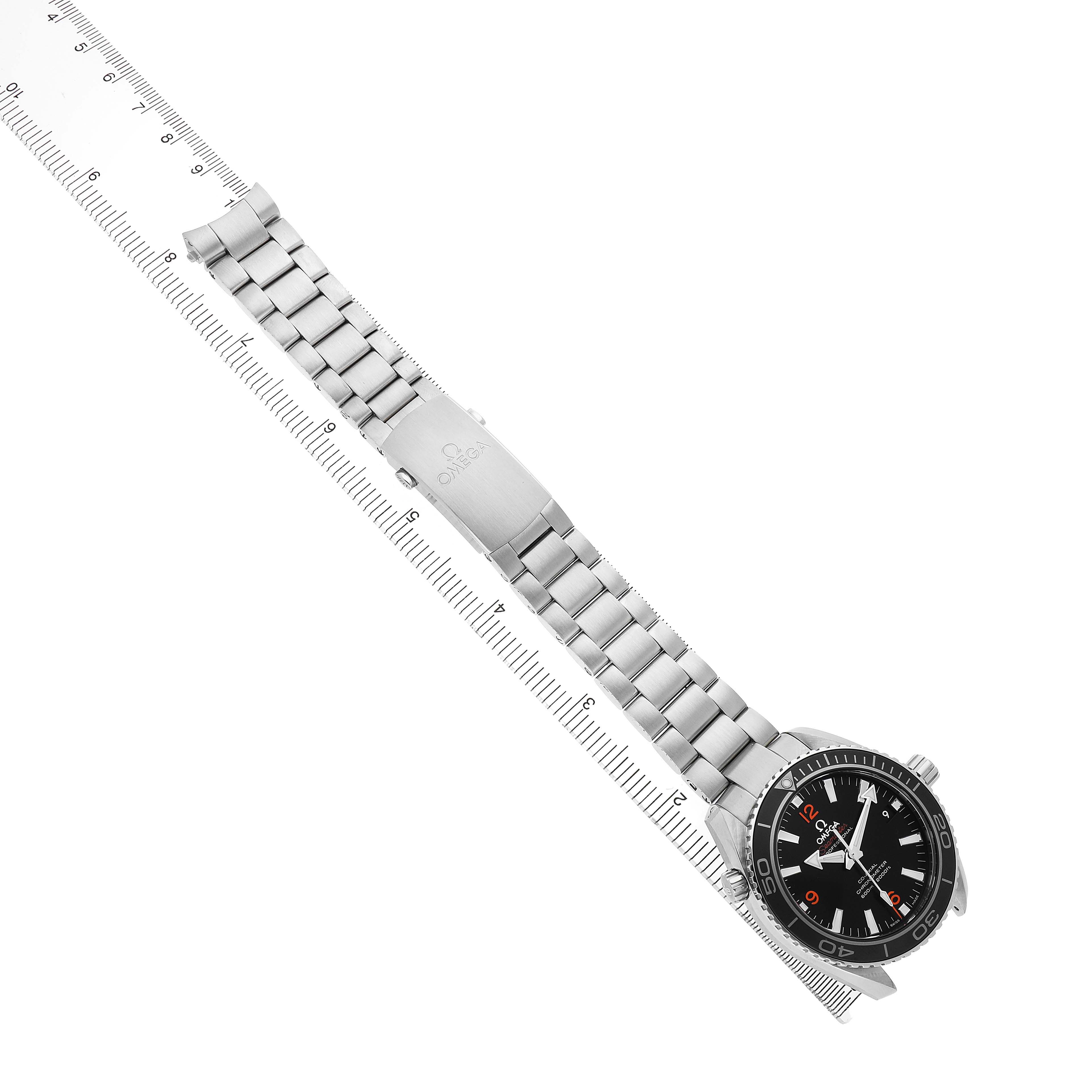 The Omega Planet Ocean 232.30.42.21.01.003 Men's Stainless Steel Black Dial watch is shown diagonally, highlighting the face, bezel, and bracelet with a ruler measuring its length.