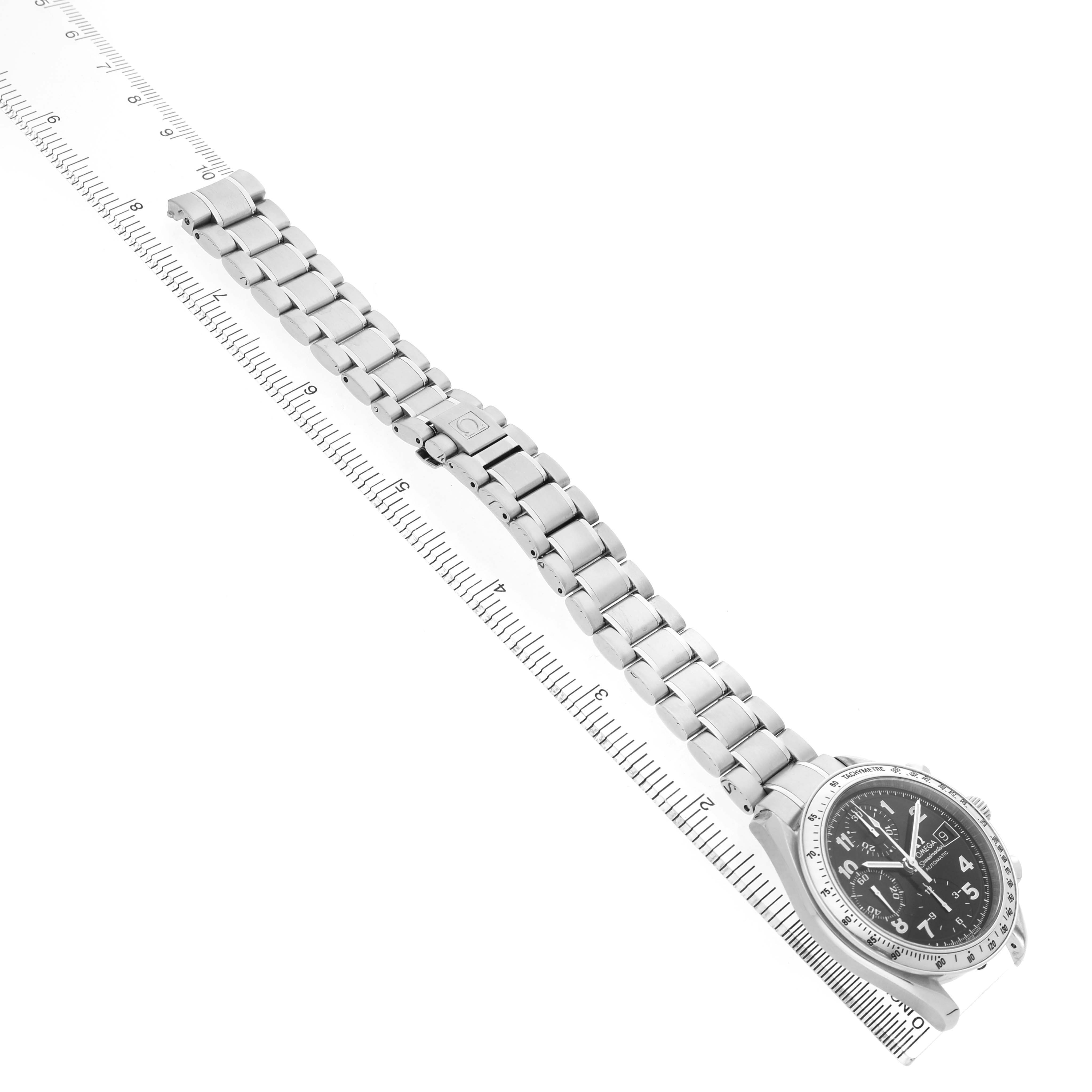 The Omega Speedmaster 3513.52.00 Men's Stainless Steel Black Dial watch is shown from a top view, featuring its bracelet and face, aligned along a ruler for scale.