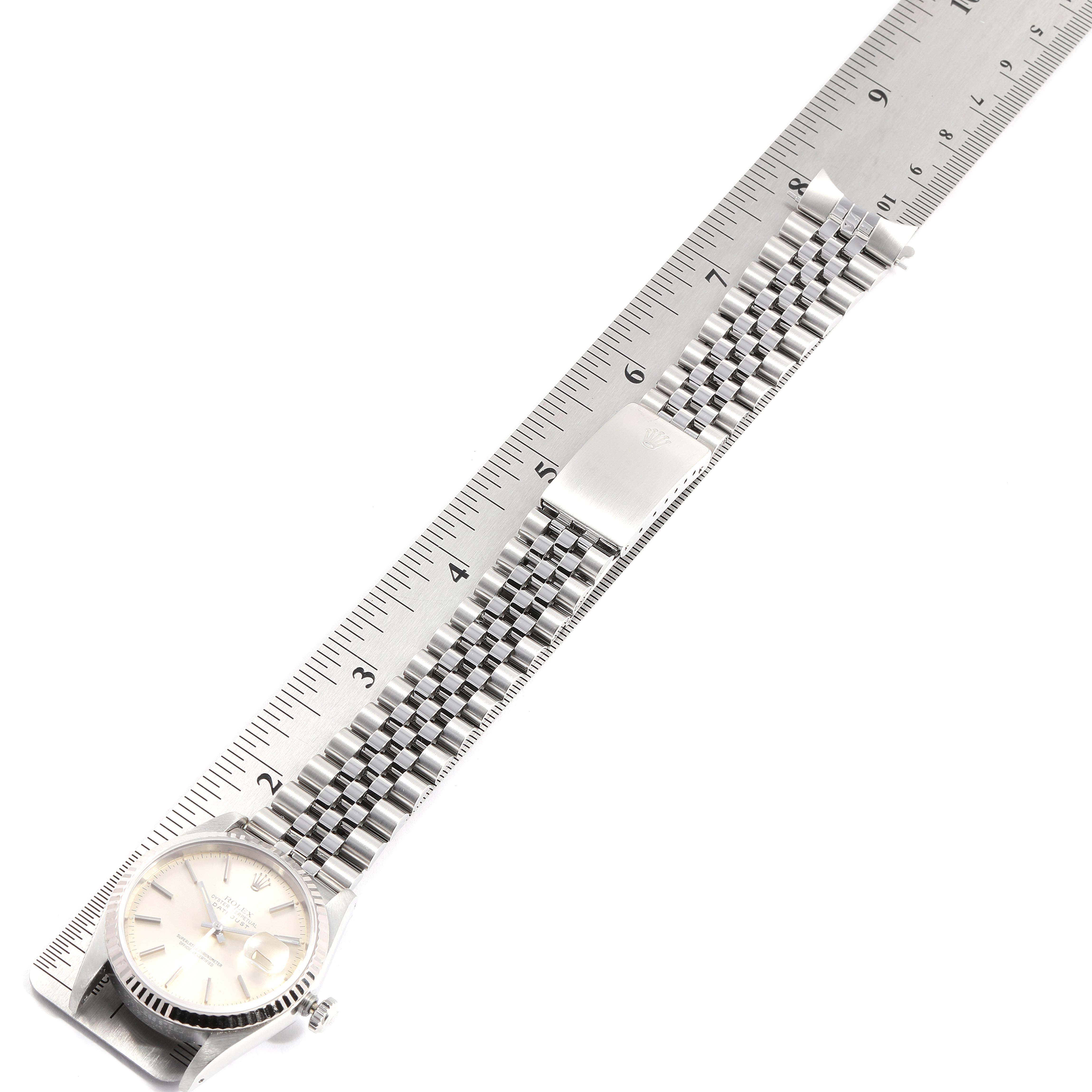 The Rolex Datejust 16234 Men's Stainless Steel Silver Dial 16234 Men's Stainless Steel Silver Dial watch is shown with its dial, crown, and metal bracelet fully extended and measured alongside a ruler.