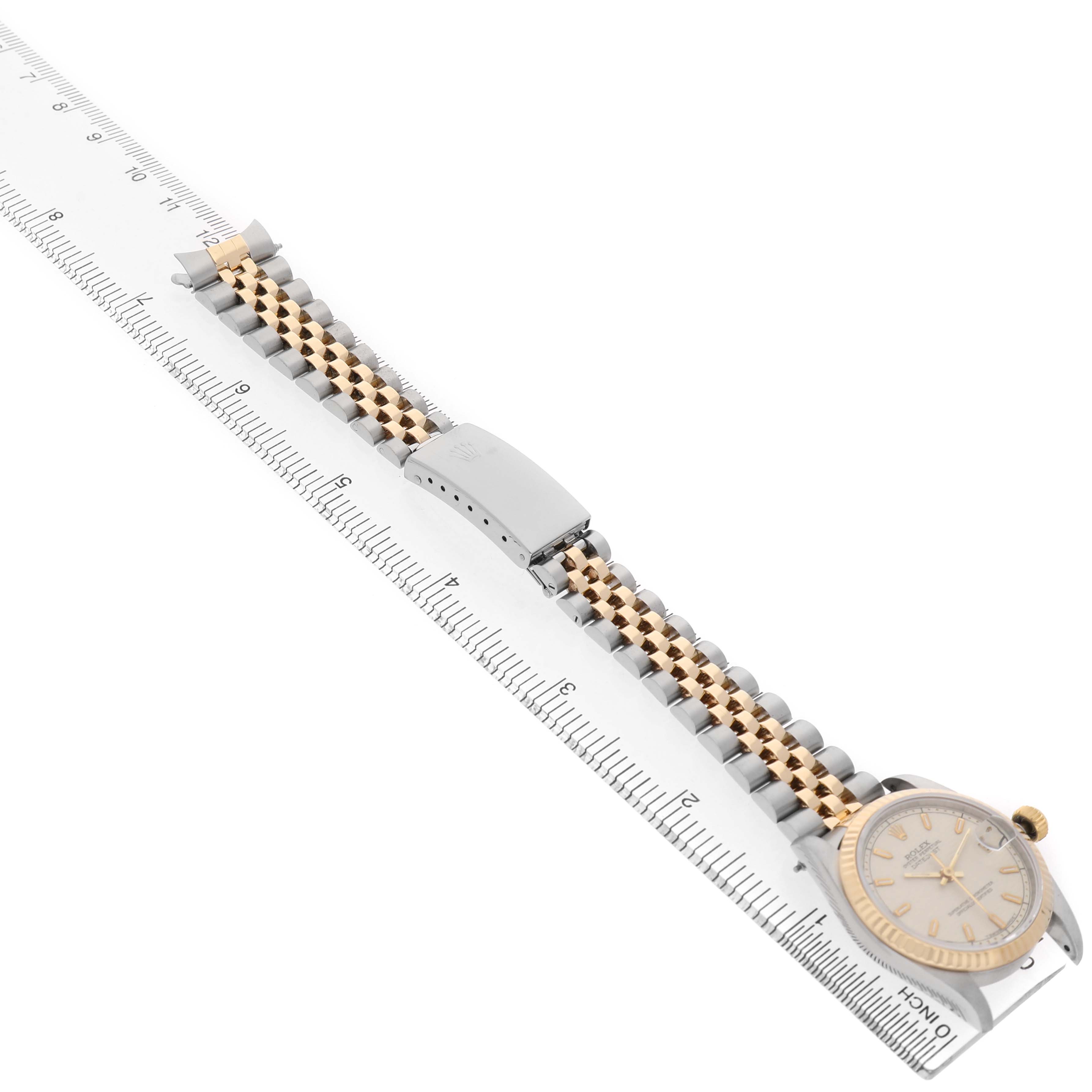 The Rolex Mid-Size 68273 Women's Steel and Gold (two tone) Beige Dial watch is shown from a side angle, highlighting the bracelet and case near a measuring ruler.